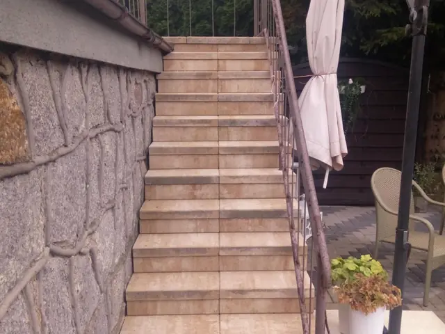 Schody zewnętrzne z beżowych płyt wzdłuż kamiennego muru